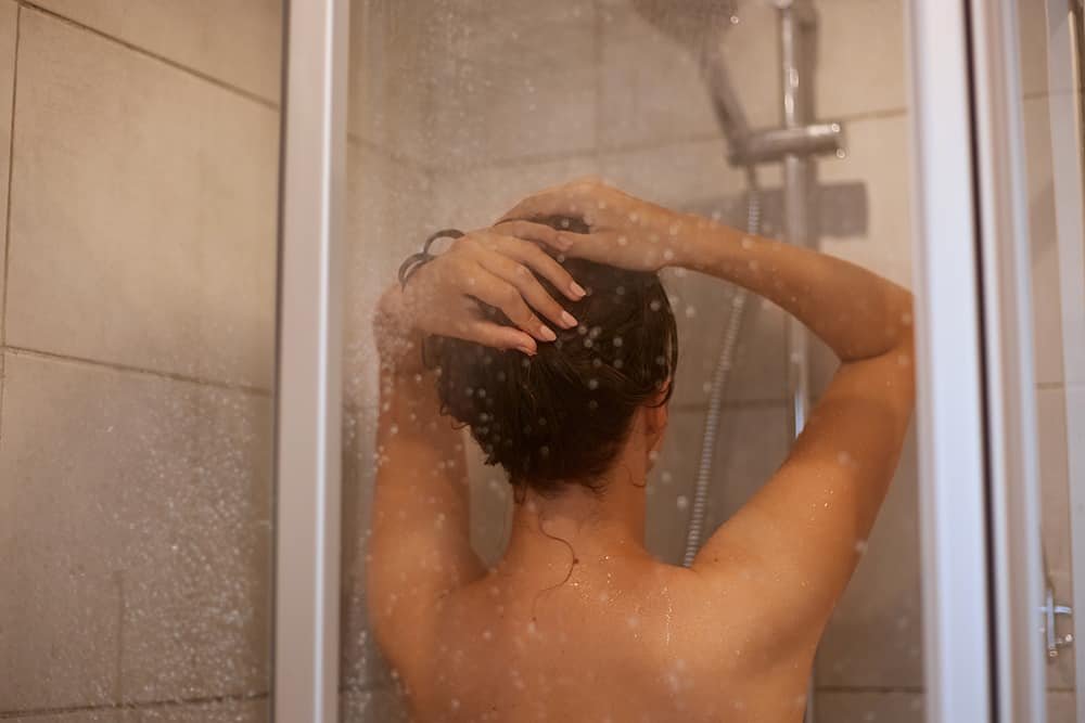 Mulher tomando banho com o chuveiro elétrico