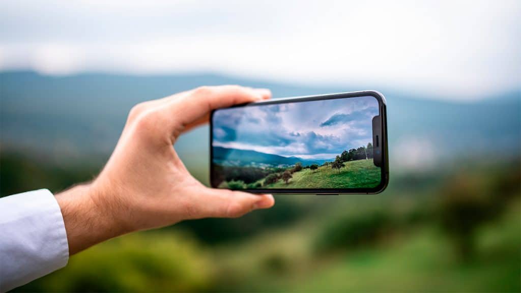 Pessoa tirando foto de paisagem com iPhone