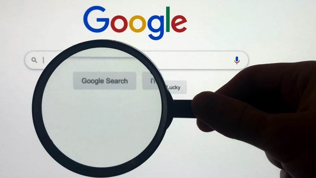 Pessoa segurando lupa sobre caixa de pesquisa do Google