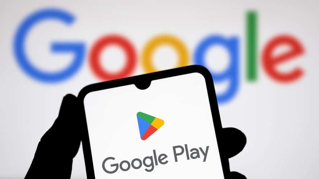 Pessoa segurando celular com imagem de logotipo da Google Play Store e ao fundo a logomarca do Google